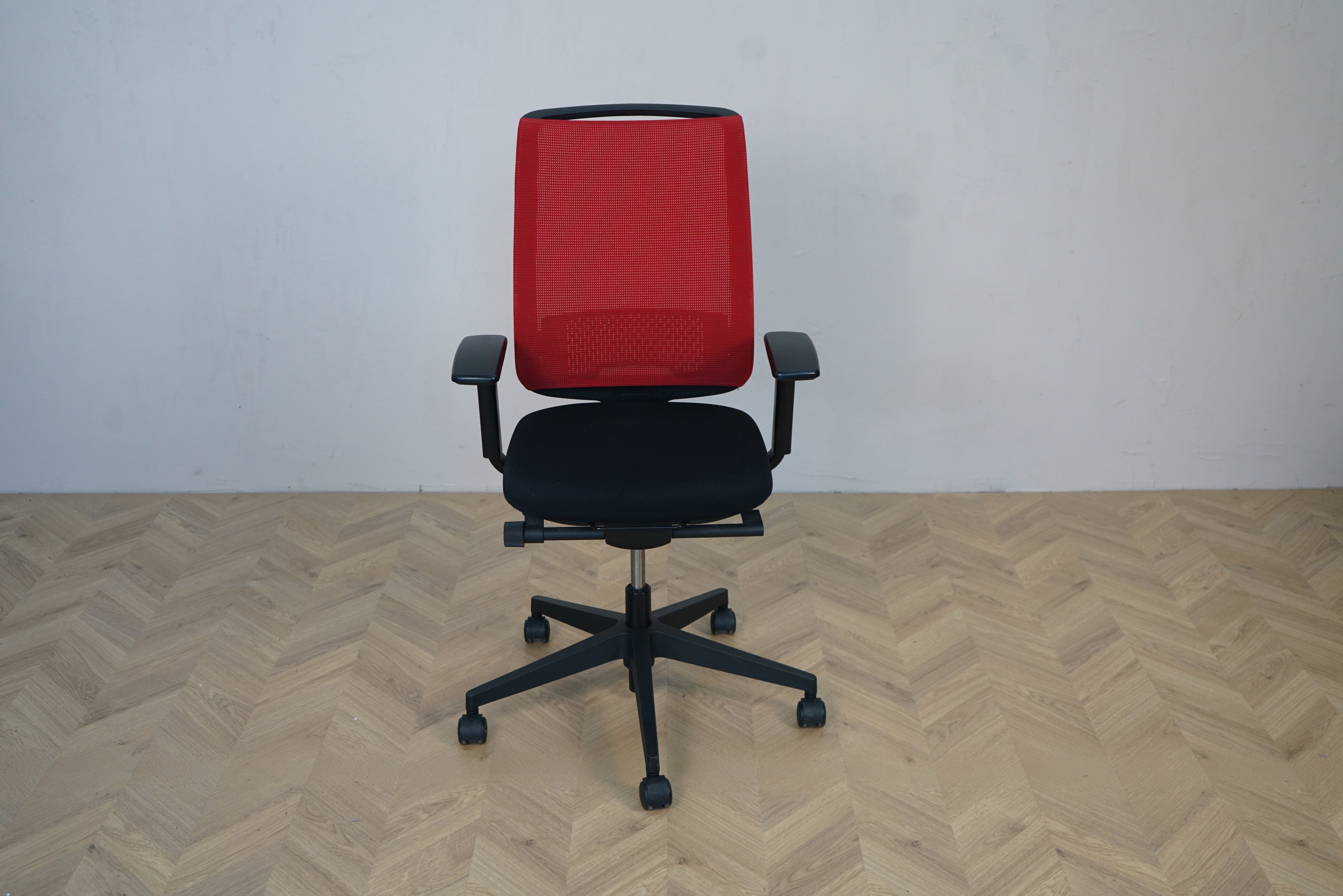 Steelcase kontorstol set forfra med rød mesh-ryg og sort sæde – ergonomisk kontorstol med armlæn